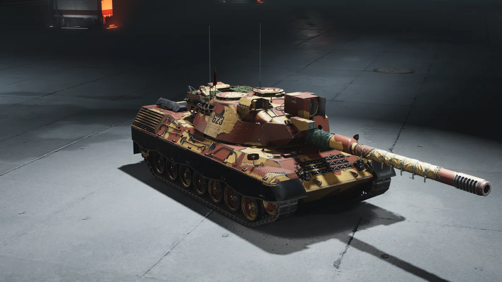 A tank with a low, flat turret in a pale khaki desert camouflage, lit from above on a plain studio floor.